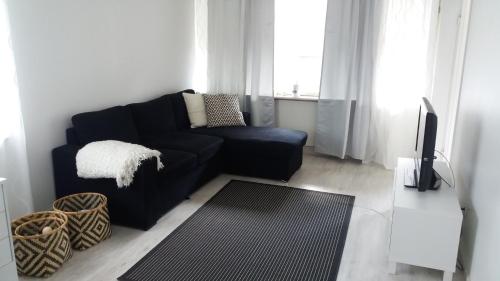 a living room with a black couch and a television at Apartment Vuorikatu 35 in Kuopio