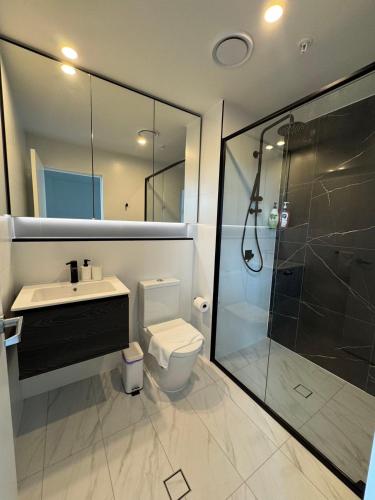 a bathroom with a shower and a toilet and a sink at Luxury 2BR Stay near Olympic Park Parramatta FREE Parking in Sydney
