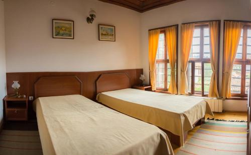 two beds in a room with two windows at Pachilov House in Zlatograd