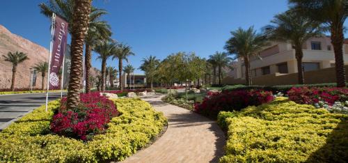 einen Gehweg in einem Park mit Blumen und Palmen in der Unterkunft Al RAHA village - Aqaba أستوديو بقرية الراحه العقبة مرسى زايد in Aqaba