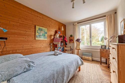a bedroom with a bed and a wooden wall at Grande maison avec extension d'architecte à 700m de la plage in Brest