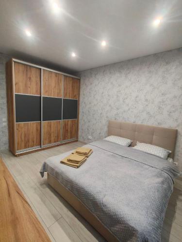 ein Schlafzimmer mit einem großen Bett und Holzschränken in der Unterkunft New Comfort Apartment in Hostomelʼ