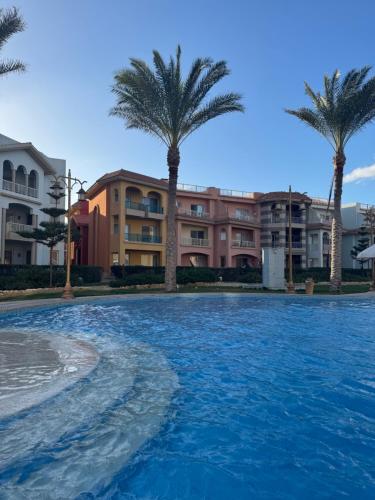 uma piscina com palmeiras em frente a condomínios em Elabd Family Porto Chalet em Marsa Matruh