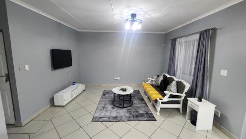 een woonkamer met een bank en een tafel bij Sunnyridge Sky East London in East London