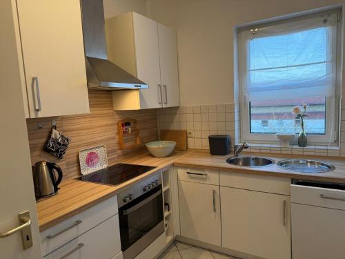 a kitchen with white cabinets and a sink and a window at Schöne Wohnung mit Aussicht in Oettingen in Bayern
