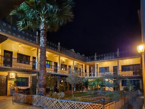 a palm tree in front of a building at night at Hotel Restaurant La Kasbah in Tinerhir