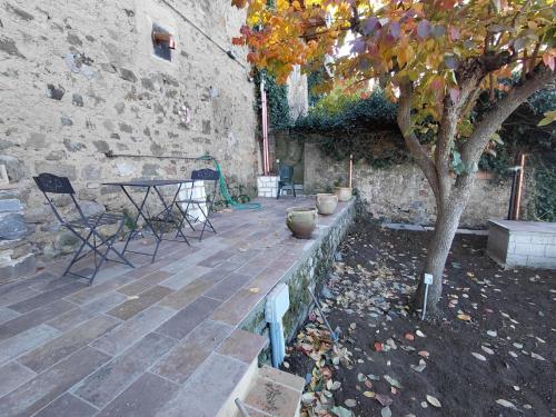 a patio with a table and chairs and a tree at La Dimora di Dida in Seggiano