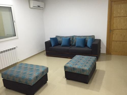 a living room with a couch and two blue pillows at Appartement Les Rosiers in Hammam Sousse