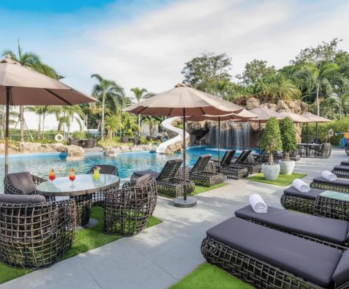 einen Pool mit Stühlen, Tischen und Sonnenschirmen in der Unterkunft Sky residences - Plage de Pattaya Pratamnak Moderne in Pattaya South