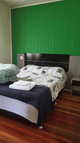 a bedroom with a bed with a green wall at Chalé Paraíso Da Serra 01 in Gramado