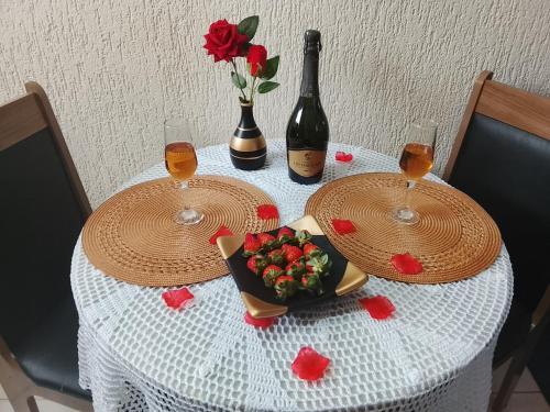 カンポス・ド・ジョルドンにあるKitnet Privativa no Portal de Campos do Jordãoのグラス2杯、ワイン1本、花