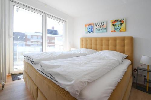 a bedroom with a bed with white sheets and a window at Fewo Gestrandet in Norderney