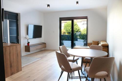 ein Wohnzimmer mit Tisch und Stühlen und einem Fernseher in der Unterkunft Royal Rest Apartments Karlovac in Karlovac