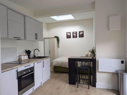 a kitchen with white cabinets and a table with a bed at Foothills Haven - Private Garden Apartment near Luas & Trails in Dublin