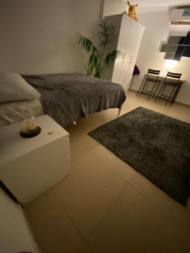 a living room with a bed and a table and a rug at Simple studio in Abu Dhabi in Abu Dhabi