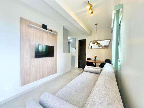 a living room with a couch and a tv on a wall at Apartamento de curta temporada - ótimo padrão - próximo Lagoa de Iriry in Rio das Ostras