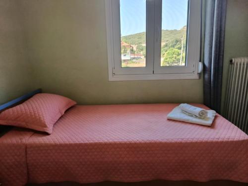 a bed with a towel and a window at Όμορφο φυσικό περιβάλλον in Filippiada