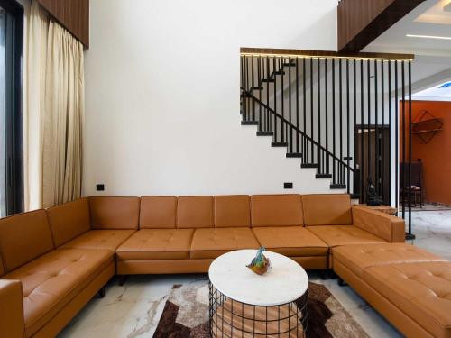 uma sala de estar com um sofá castanho e uma mesa em Villa Papillon by DanCenter | Pvt Pool | Jacuzzi | Kids Room | Udaipur em Thūr