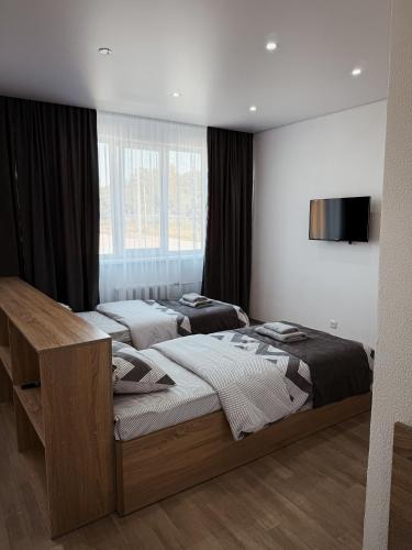 a bedroom with two beds and a television on the wall at Поділля in Netishyn