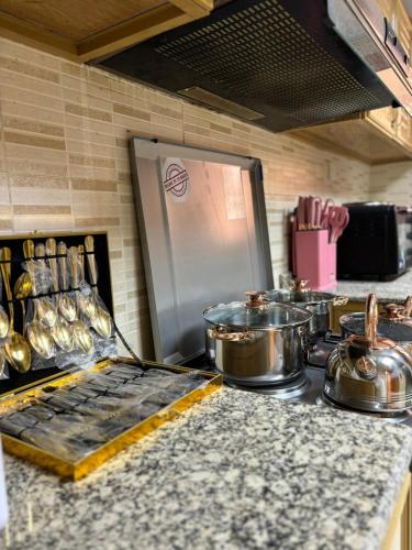 eine Küchenarbeitsplatte mit Töpfen und Pfannen sowie einem Kühlschrank in der Unterkunft Opera413 Spacious & Central in Muscat