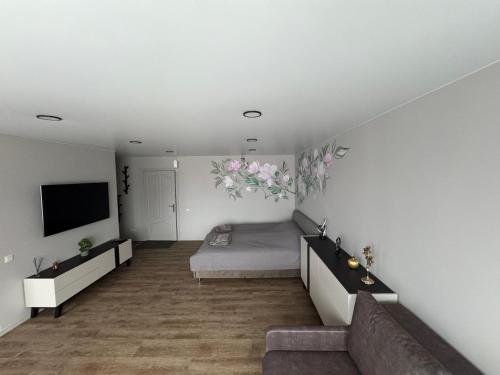 a bedroom with a bed and a couch and a tv at JK apartment in Rēzekne