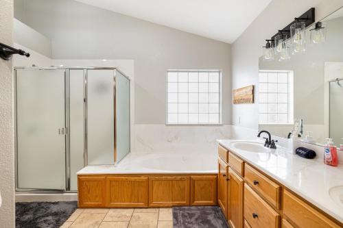 Un baño con bañera, ducha y lavabo. en Forest Heights Mountain Views Hot Tub Heated Floors Pizza Oven, en Flagstaff