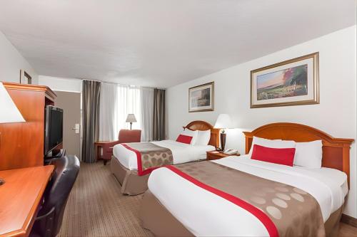 a hotel room with two beds and a desk at Iberia House & Suites in New Iberia