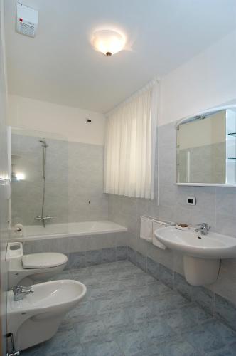 a bathroom with two sinks and a bath tub at Hotel Karinhall in Trento