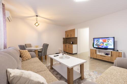 a living room with a couch and a tv and a table at NolE Apartments in Visoko