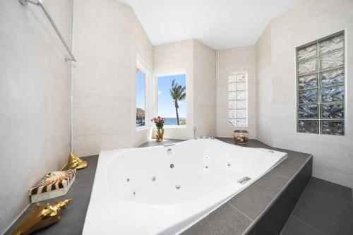 a large white tub in a bathroom with a window at Private Beach Ocean Front Boat Dock Tiki Bar in Savaneta