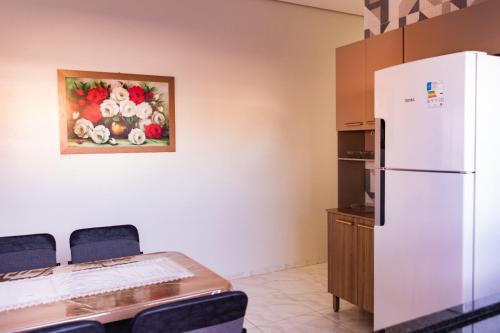 a kitchen with a table and a white refrigerator at Casa Acqua Beach in Vilhena