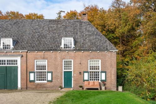 una casa de ladrillo con una puerta verde y un banco en De Zwaluwenburg, en 't Harde