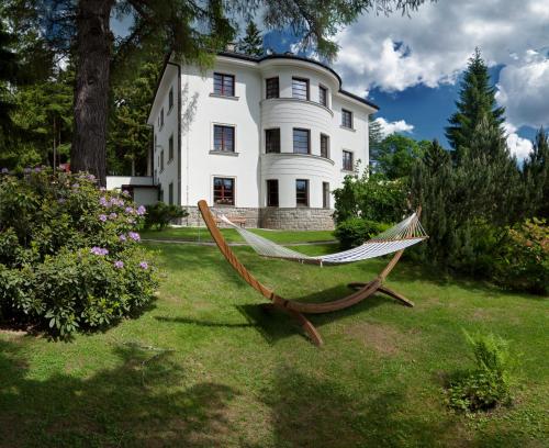 a hammock in front of a large house at Hotel Bedriska Wellness Resort & Spa in Špindlerův Mlýn