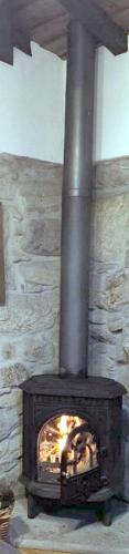 a fireplace with a fire in it with a stone wall at Casa da Avó in Sistelo
