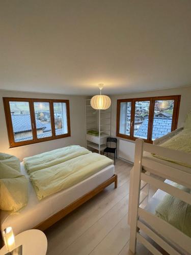 a bedroom with a bed and a desk and windows at Apartments Soldanella in Leukerbad