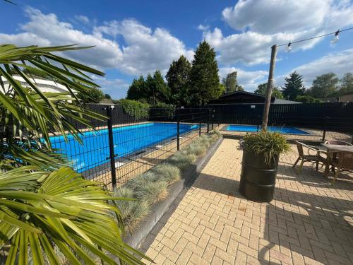a fence around a pool with a table and a bench at Tiny Cabin Sole op de Veluwe in Putten