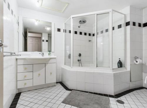 a white bathroom with a shower and a sink at 2-Bed Unit with Balcony BBQ & Stunning Lake Views in Belconnen
