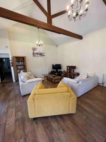 a living room with two couches and a chandelier at The Old Hay Barn - Games Room, Gym, Sleeps 8 in Godmanchester