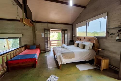 a bedroom with a bed and a bench and windows at Chalés São Francisco II in Santo Antônio do Pinhal