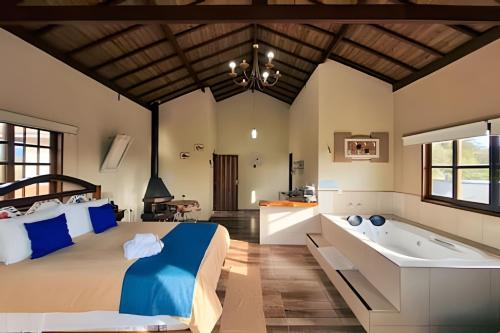 a bedroom with a large bed and a bath tub at Chalés São Francisco II in Santo Antônio do Pinhal