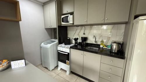a small kitchen with a stove and a microwave at Flat funcional e moderno em Uvaranas-com elevador in Ponta Grossa