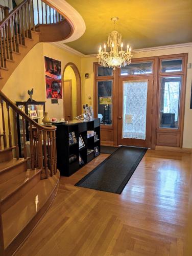 a living room with a staircase and a chandelier at Chateau Murdock Gite in Saguenay