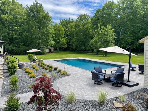 a swimming pool with two chairs and a table and an umbrella at Private 5-Acre Retreat In-Ground Pool Hot Tub in Oberlin