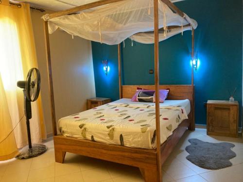 a bedroom with a canopy bed and a blue wall at maison rio la rufisquoise in Saly Portudal