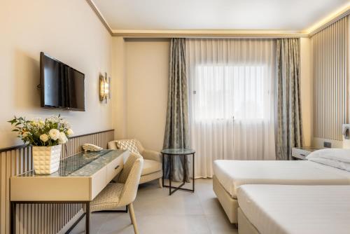 a hotel room with two beds and a couch and a tv at Abacus Hotel in Sesto San Giovanni