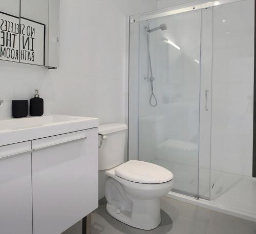 a white bathroom with a toilet and a shower at The Downtown Oasis in Montréal