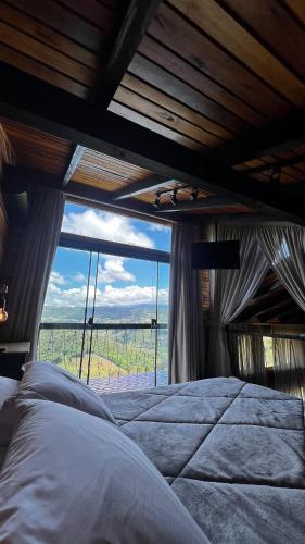 a bed in a room with a large window at The Valley Cabin in Barracão
