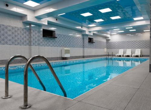 a swimming pool with blue water in a building at Alis Business Hotel baku in Baku