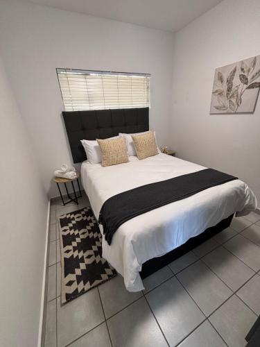 a bedroom with a large bed and a window at Waterfall Smart Apartment 2bed2bath in Midrand