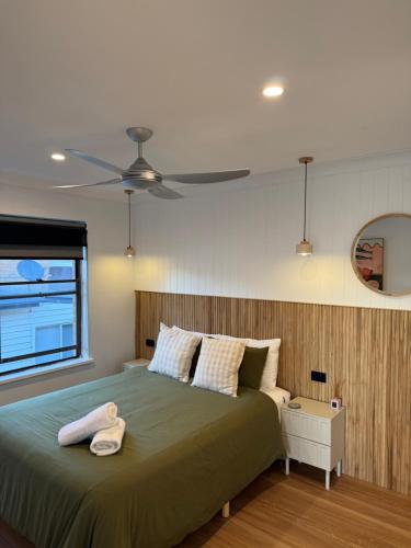 a bedroom with a green bed with a ceiling fan at Waters Edge - Dunbar Court - Central Location in South West Rocks